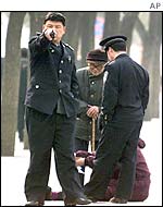 Chinese police remove an elderly couple protesting outside the NPC