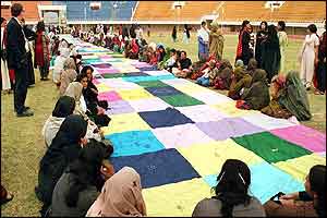 Afghan and Pakistani women stitch a large embroidery panel in Islamabad