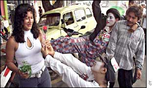 Clowns campaigning for congressional candidate Cesar Carrera offer a flower to a woman in Florencia, Colombia