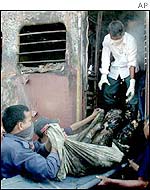 Relief workers remove a body from one of the burned cars of the train set on fire by a mob in Godhra, India 