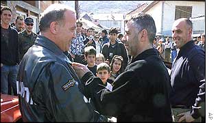An ethnic Albanian man shakes hands with a member of an ethnically mixed police patrol in Radusa