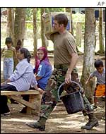 US special forces soldier state walks past residents as he carries a plastic bucket and medical supplies, Campo Uno