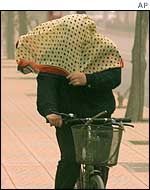 A cyclist tries to cover herself with a scarf
