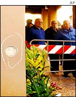 Onlookers and flowers at the scene of the murder