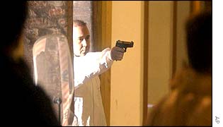 An Italian policeman holds a pistol during a forensic simulation at the scene