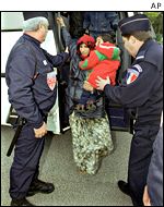 French police escort a refugee woman with a baby from a bus