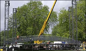 Workmen constructing stage with the help of a crane