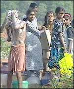 Tamil boy bathing and girls collecting water at the well in a refugee camp