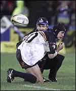 Stephen Larkham receives treatment to his elbow as play goes on around him