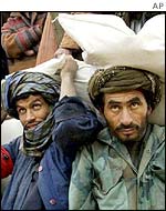 Afghan men carry sacks of donated wheat