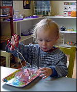 boy using tongs to move shaped objects