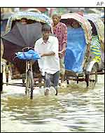 Dhaka rickshaw pullers wade through rain water