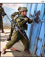 An Israeli soldier uses a sledge hammer to smash a door in Balata refugee camp, Nablus