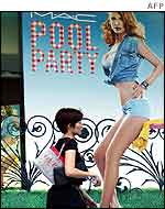 A Singaporean woman walks past a poster of a model