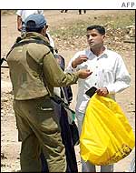 An Israeli soldier questions a Palestinian man at a checkpoint