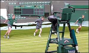 Ground staff pull the covers across Number One Court