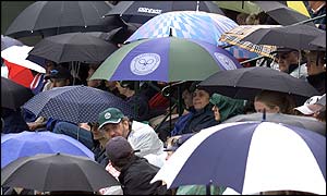 Fans shelter from the rain as play is postponed at SW19