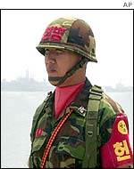 A South Korean military police officer with warships in the background