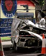 A woman passes a burnt-out van on the lower Newtownards road in Belfast 