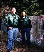 Police officers next to gang graffiti