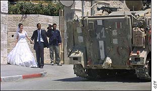 Newly weds pass Israeli armoured vehicle