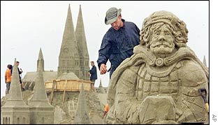 Sand sculpture with sand church in the background