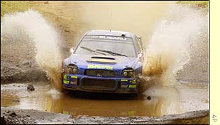 Finland's Tommi Makinen's passes through a flooded river in his Subaru Impreza 