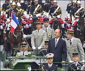 French President Jacques Chirac (in suit) stands on a command car to review troops in the parade