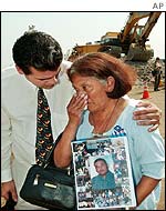 A mother carrying a picture of her son is comforted