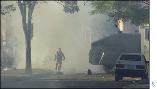 A police officer runs through tear gas in front of the Parliament Building in Asuncion on Monday