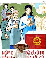 A Vietnamese woman walks by an election poster