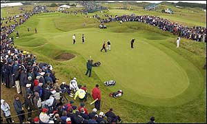 Tiger Woods putts out on the 13th surrounded by huge crowds