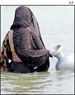 Bangladeshi woman wades through flood water