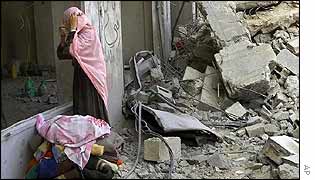 Palestinian woman looks at rubble of building destroyed in Tuesday's air strike