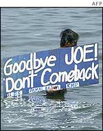 A swimmer displays an anti-US placard