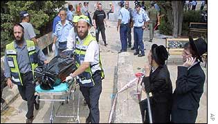 Two ultra-orthodox Jews look on as a bomb victim is taken away