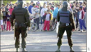 Police block a street while people wait for food to be donated, outside of Montevideo