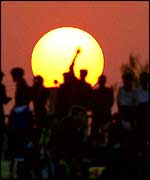 Sun and silhouetted figures PA 