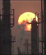The Sun sets behind an oil refinery
