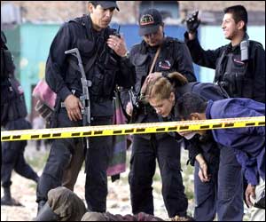 Police examine the body of a victim from one of the explosions in Bogota