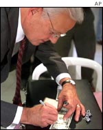 US Treasury Secretary Paul O'Neill signing dollar bills for children at a play centre