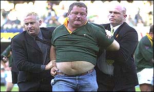 The Springbok supporter is escorted off the field 