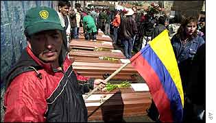 Man holds Colombian flag over bodies of victims of mortar attack 