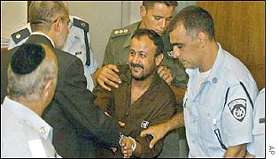 Marwan Barghouti (centre) greets his lawyer (left) as he is escorted into the courtroom
