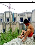 A boy sits near the construction of the Three Gorges dam