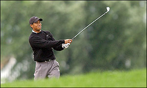 Tiger Woods hits a a three-iron onto the 18th and secures a miraculous birdie and a rain-delayed 69