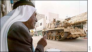 Palestinian man watches tank roll past near Ramallah