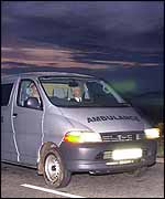 An ambulance carrying the bodies leaves the woodland