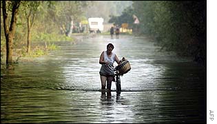 Woman pushes bike along flooded road