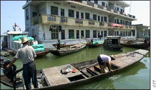 Chinese fishermen drive a boat past a flooded residential building on Dongting Lake 